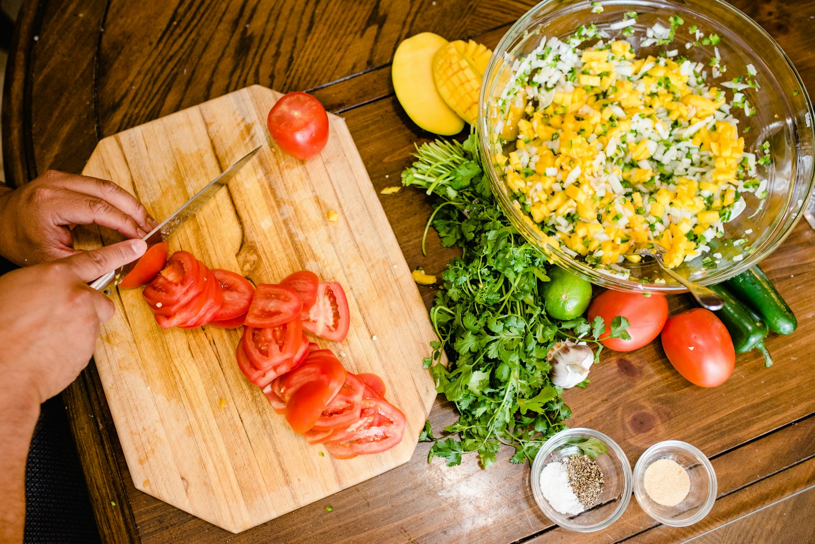 Hands preparing fresh tomatoes on a wooden chopping board